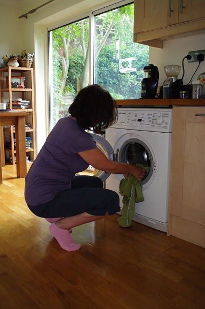 Woman squatting to load washing machine