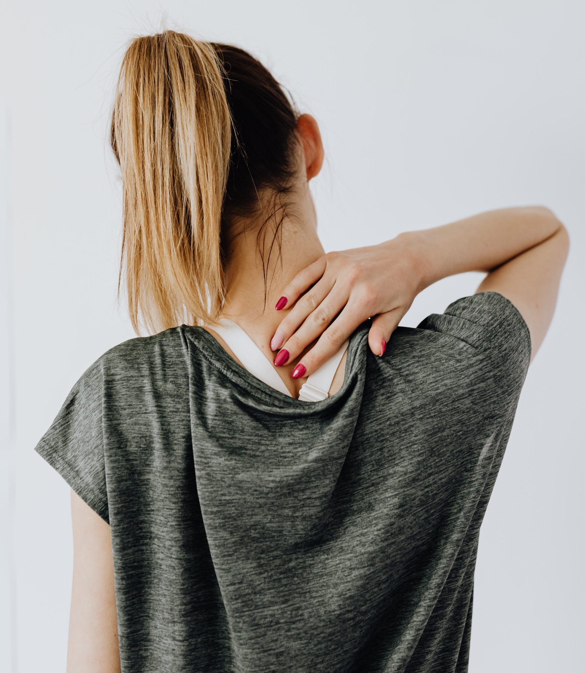 Woman holding the back of her neck, looking like she is in pain