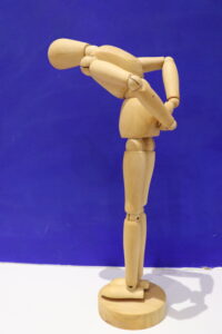 Photo of artist's wooden model of a person bending over holding their back