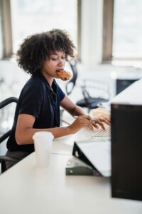 Photo showing woman eating while working at her desk