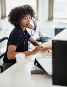 Photo showing woman eating while working at her desk
